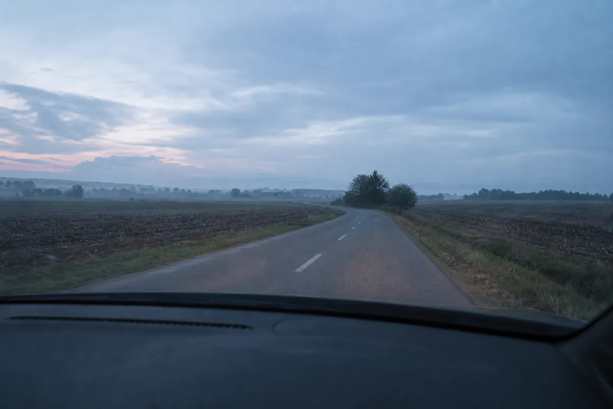 Route départementale vide entre deux champs, lumière bleutée de fin de journée